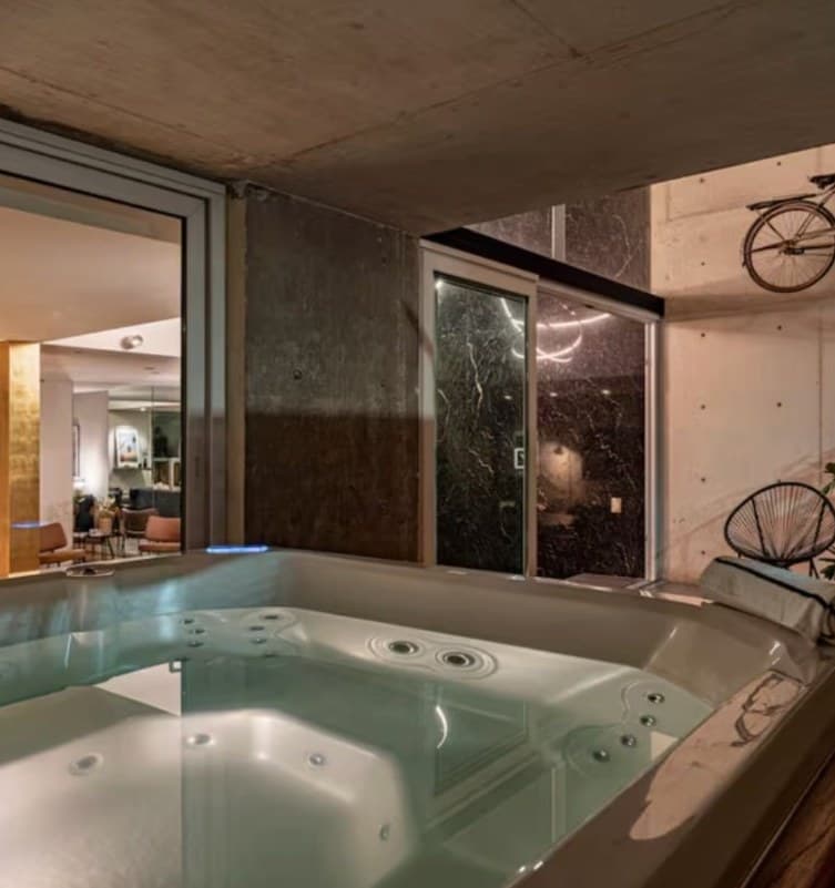 Indoor hot tub beside a concrete wall and glass doors