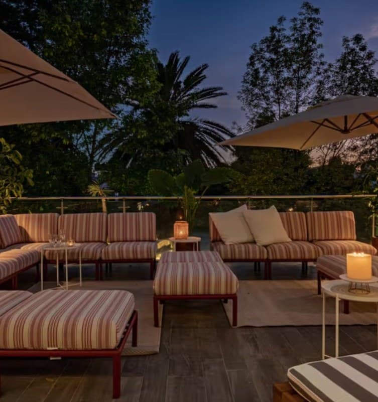 Rooftop terrace at dusk with striped lounge seating, candles and palm trees